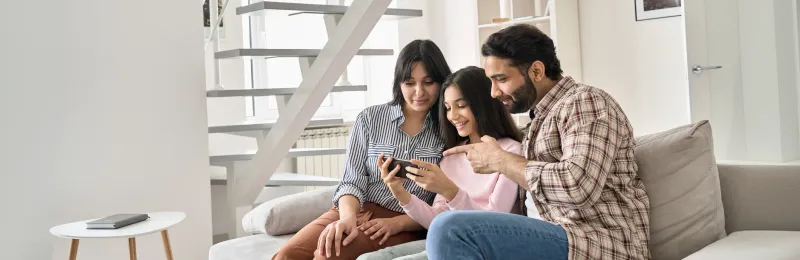 famiglia sul divano che guarda insieme lo smartphone dopo aver attivato luce e mobile con Enel